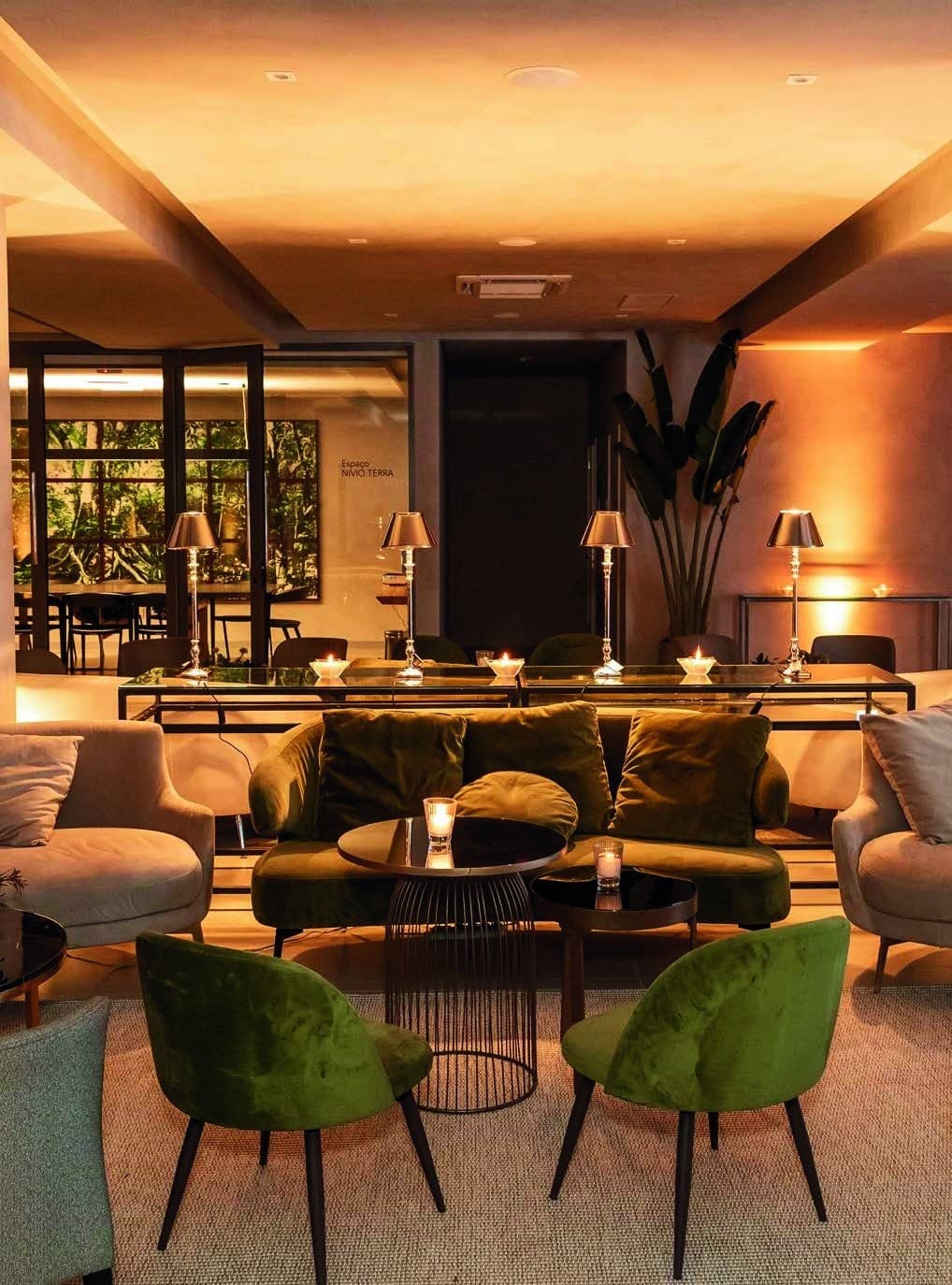 Lounge intimista com poltronas verdes e iluminação quente