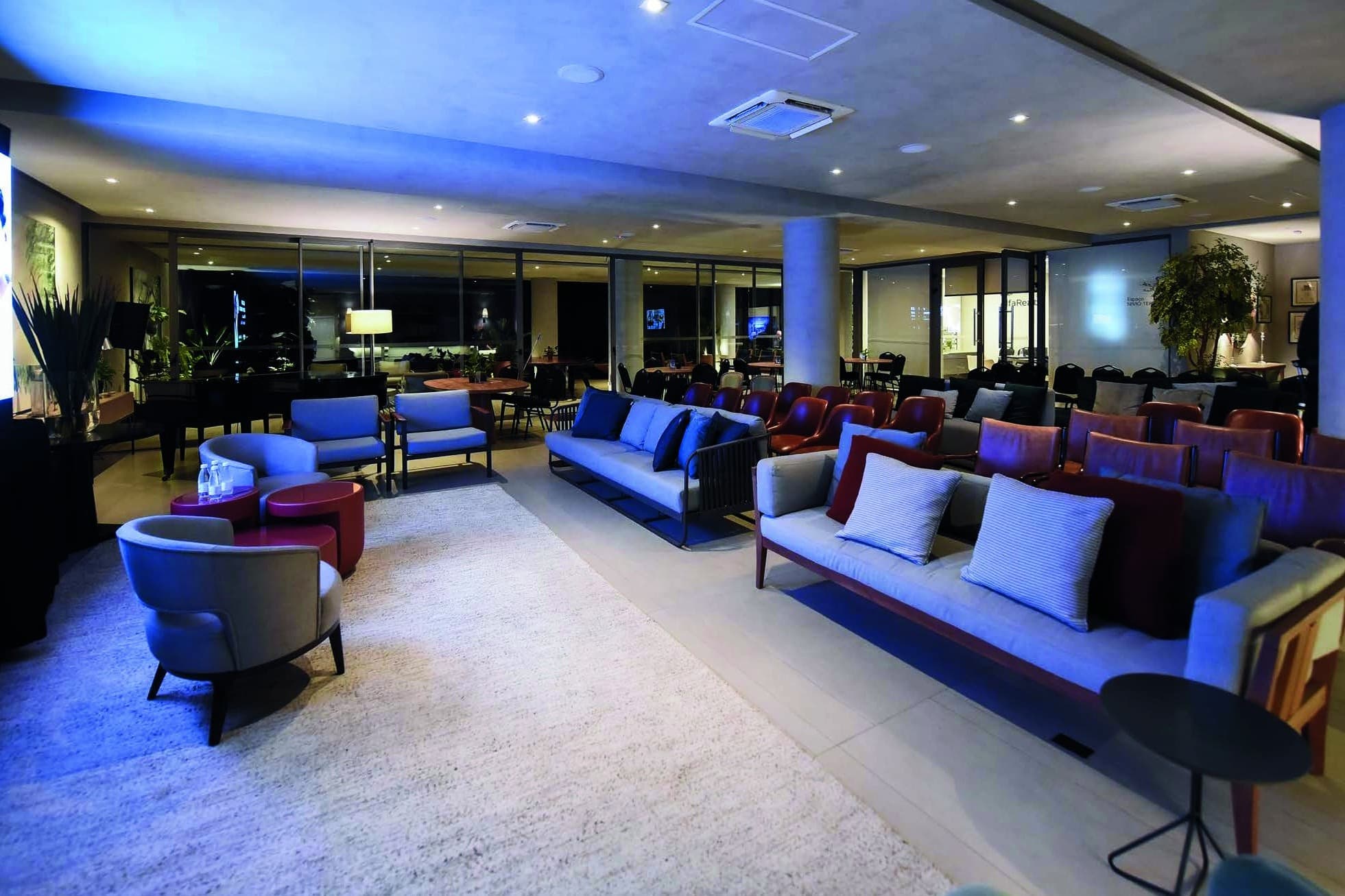 Lounge amplo com sofás e iluminação azul em montagem para evento